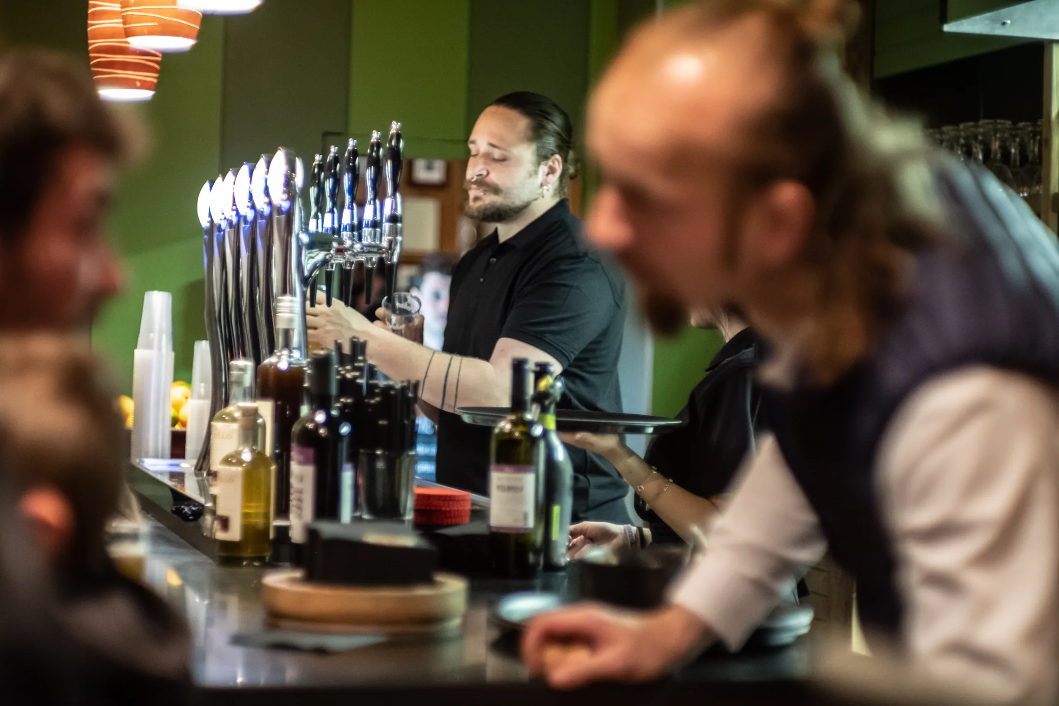Lo chef Mattia Giacomelli intrattiene un ospite mentre sullo sfondo il barman spilla una delle sette birre alla spina