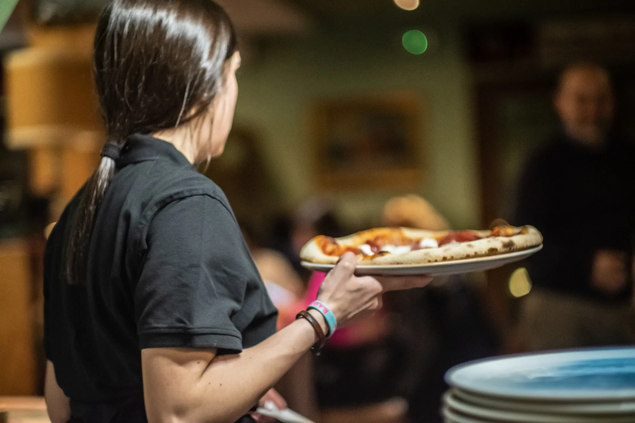 Una giovane cameriera di Rebelot sta portando la pizza al tavolo